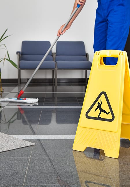 photo man with mop and wet floor sign